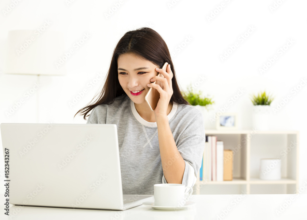 young Woman working on laptop and talking on the phone young Woman working on laptop and talking on the phone