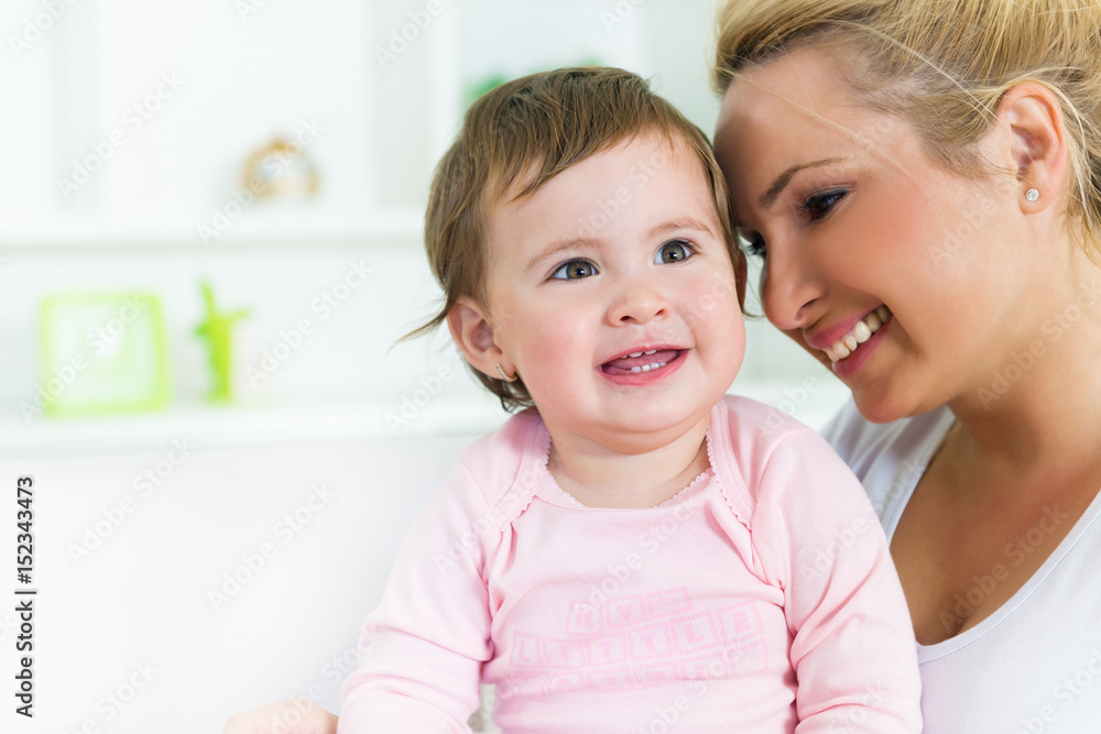 Smiling mom and baby sitting on the couch together.Baby looking away.Shallow doff Smiling mom and baby sitting on the couch together.Baby looking away.Shallow doff