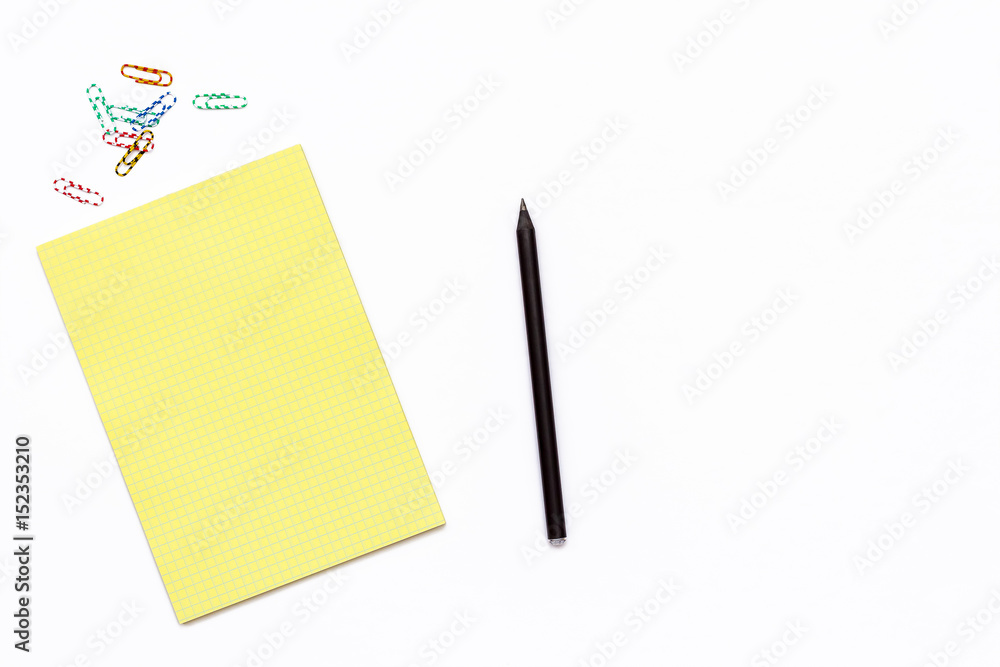 yellow Notepad, a pencil and a paper clip. Minimal business concept of working place in the office yellow Notepad, a pencil and a paper clip. Minimal business concept of working place in the office