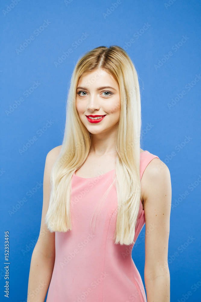 Smiling Young Woman in Pink Dress on Blue Background. Portrait of Pretty Girl in Studio. Smiling Young Woman in Pink Dress on Blue Background. Portrait of Pretty Girl in Studio.