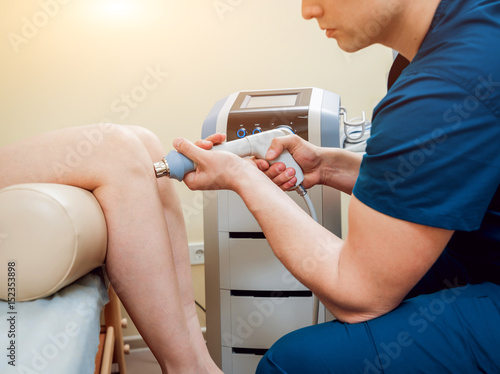 Shock wave therapy. The magnetic field, rehabilitation. Physiotherapist doctor performs surgery on a patient's knee photo