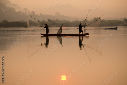 Fisherman catching fish at dawn in Thailand