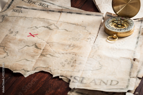 Top view to table with vintage map with abstract Island and nautical compass.