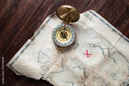 Top view to fake Pirates Vintage map of Treasure Island with red cross on wooden table
