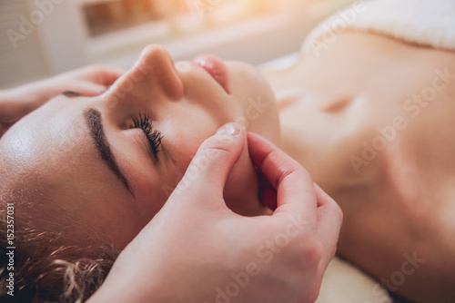 Beautiful woman in spa salon getting facial massage photo