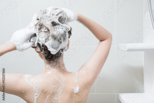 woman in shower washing hair with shampoo