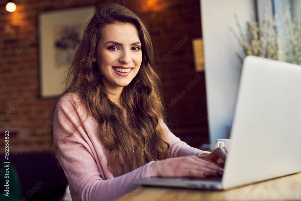 Portrait of young woman sitting with laptop at cafe Portrait of young woman sitting with laptop at cafe