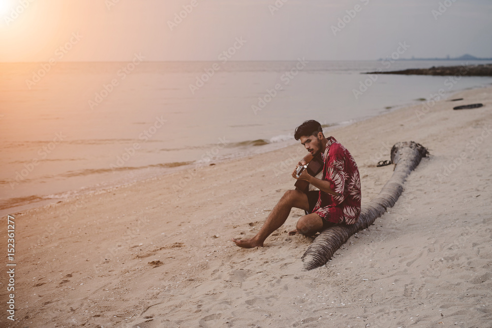 Young man playing the guitar on the beach. Young man playing the guitar on the beach.