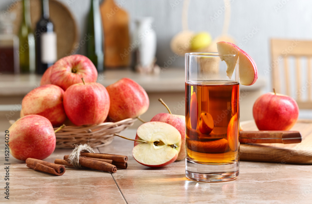 Glass of apple juice and ripe pink apples on a kitchen table Glass of apple juice and ripe pink apples on a kitchen table