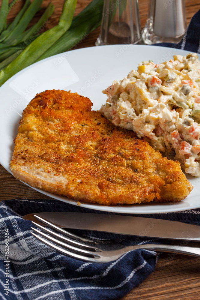 Fried pork chop in breadcrumbs, served with vegetable salad. Fried pork chop in breadcrumbs, served with vegetable salad.