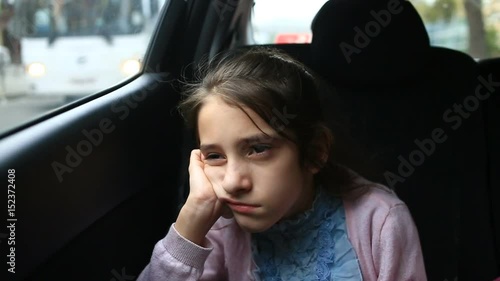 Little girl, bored in the car - looking out the window through the window - street reflection