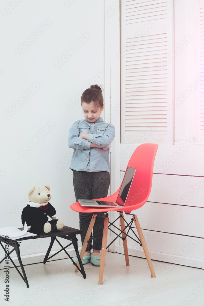 little girl working on laptop with teddy bear