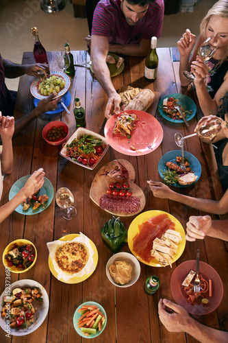 Overhead shot of friends passing food across a dinner table