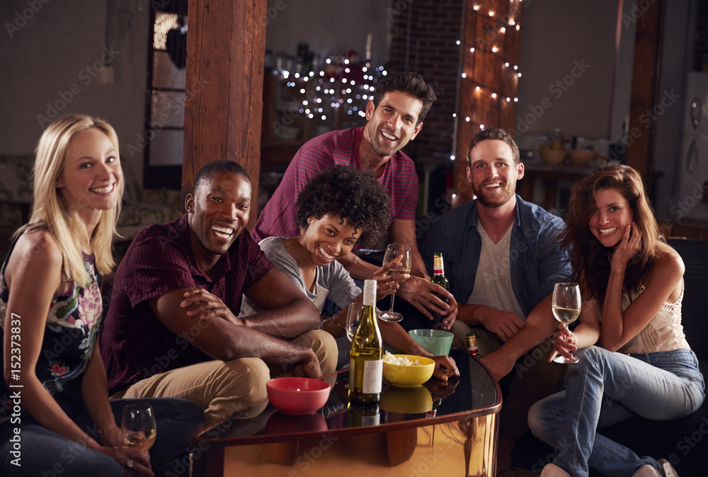 Young adult friends having a party at home look to camera