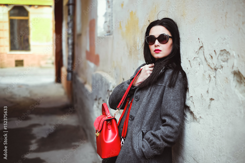 Obraz premium Long hair girl near old wall with red backpack