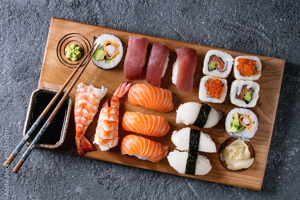 Sushi Set nigiri and sushi rolls on wooden serving board with soy sauce and  chopsticks over black stone texture background. Top view with space. Japan  menu Stock Photo