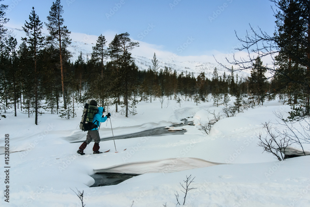 Tourist in Russian Lapland crossing unfrozen river, Kola Peninsula