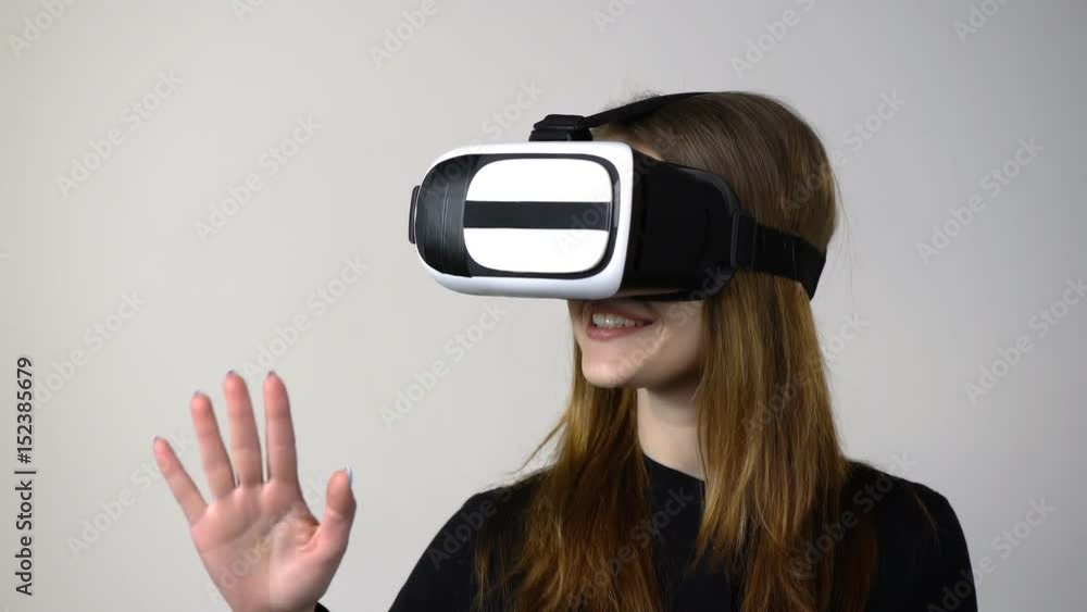 Casual young woman wearing virtual reality goggles moving hand, locked down video Casual young woman wearing virtual reality goggles moving hand, locked down video