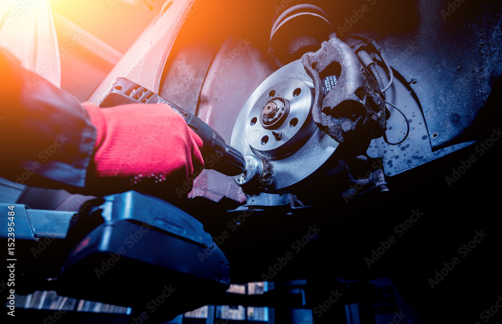 Cleaning disc brake on car, in process of new tire replacement. Stock