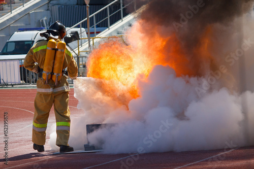 Firefighter in equipment extinguishes fire with a fire extinguisher