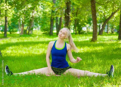 Sporty woman doing splits on green grass