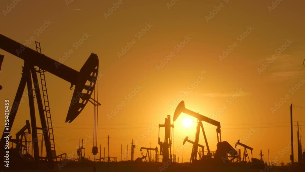The silhouette of oil pumps in a large oil field at sunrise. The silhouette of oil pumps in a large oil field at sunrise.
