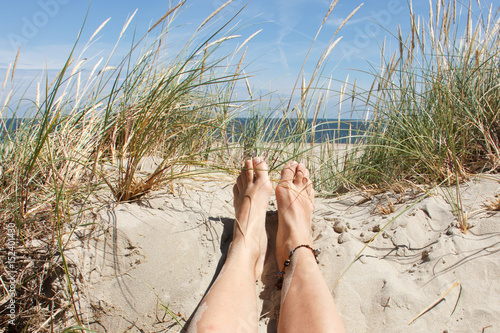 Lady's feet lying in the sand on a dune on a sunny day on the island of Texel, The Netherlands.