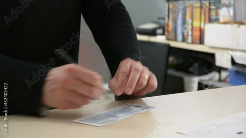 Male hand signing cheque and receiving document or contract from other person's hands, in office environment