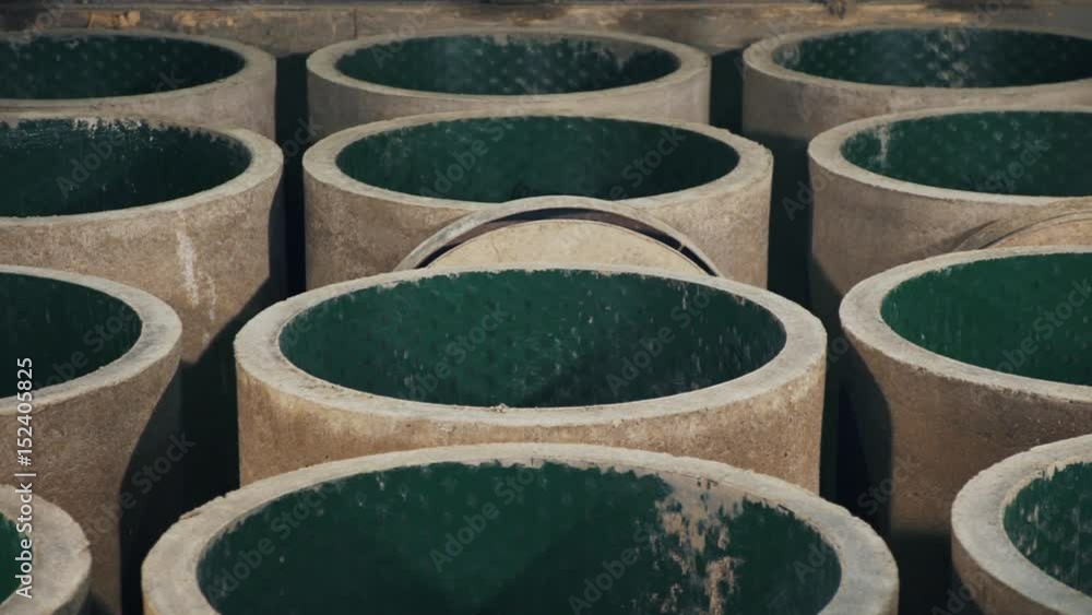 New grey concrete manholes with green plastic inside at factory storage place, panoramic shot New grey concrete manholes with green plastic inside at factory storage place, panoramic shot