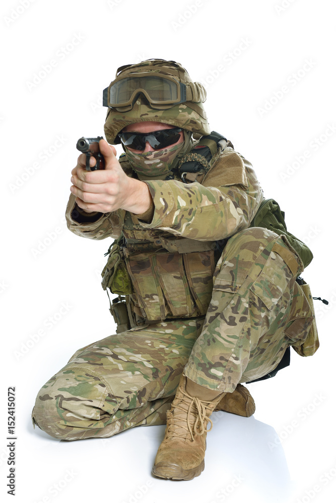 Military man in camouflage uniform, armor vest, dark glasses and helmet with gun aiming at the enemy Military man in camouflage uniform, armor vest, dark glasses and helmet with gun aiming at the enemy
