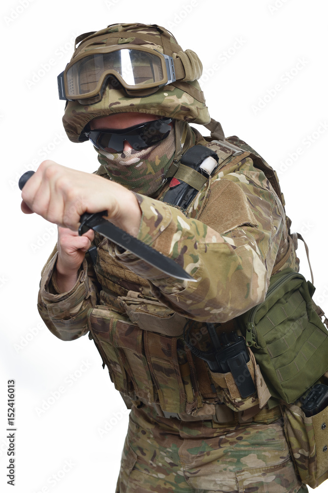 Military man in camouflage uniform, armor vest, dark glasses and helmet with knife, isolated on white background