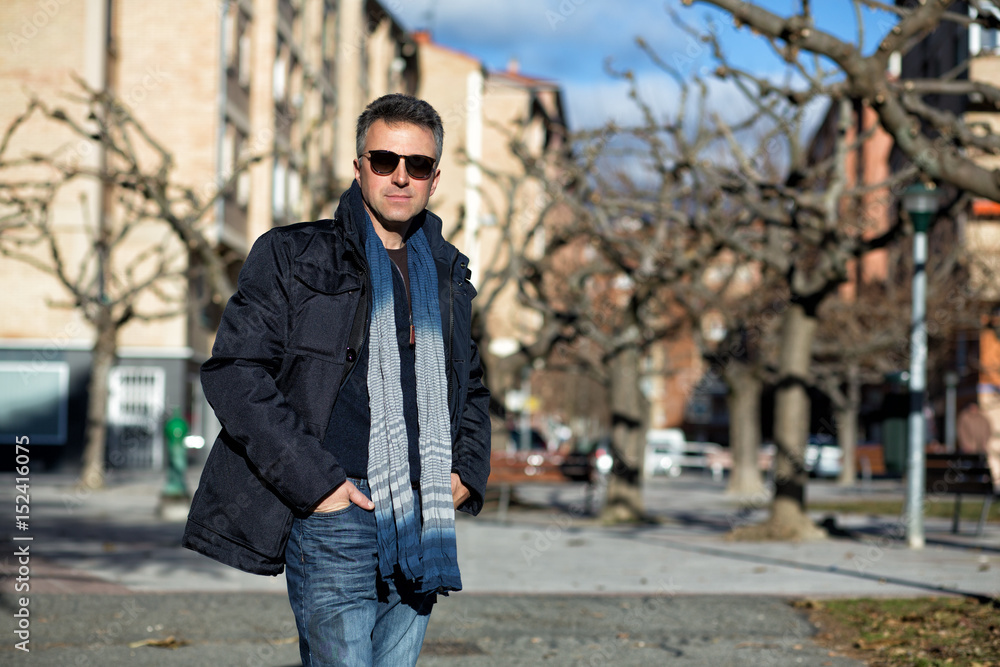Handsome happy smiling man. Outdoor winter male portrait. Attractive confident middle-aged man in sunglasses walking in city.
