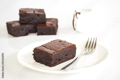 Sliced brownies on white plate. Served with chocolate fudge. On white plate over white background. Sweet and moist chocolate dessert.