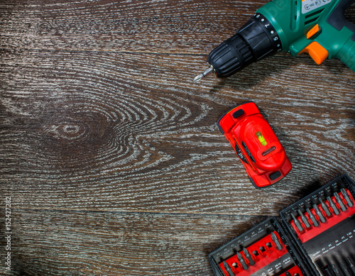 941912 Screwdriver, laser level and a set of attachments. Tools on a wooden background.