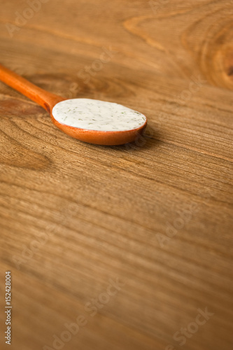 Sour cream sauce with dill in the wooden spoon. Wood background.