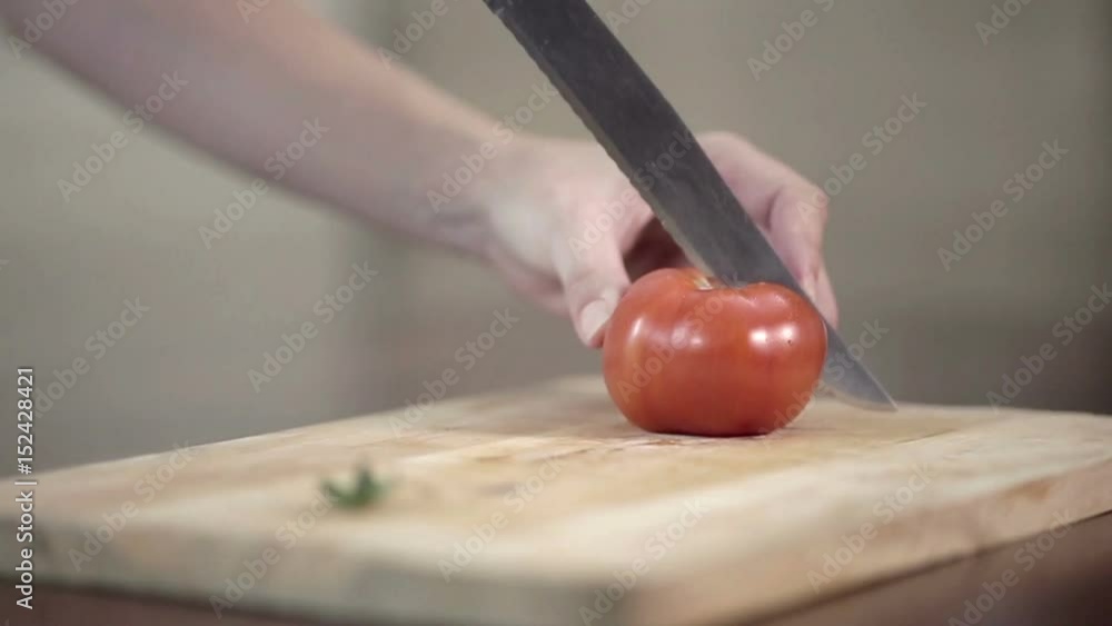 Close-up of professional Cook Chopping tomato on cutting board, young woman preparing meal at the kitchen table. Close-up of professional Cook Chopping tomato on cutting board, young woman preparing meal at the kitchen table.
