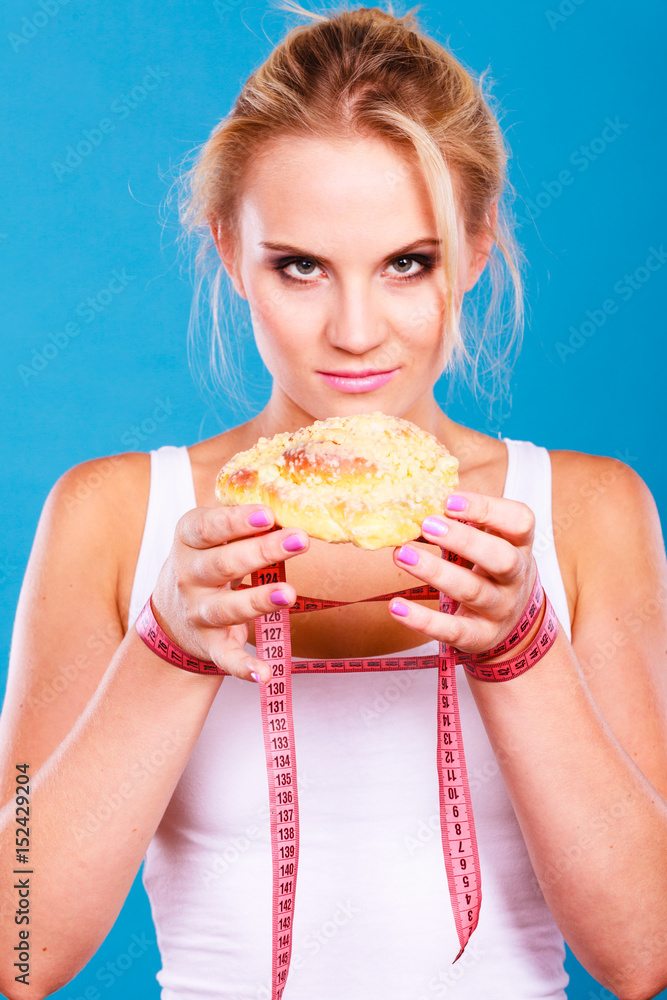 Woman holds sweet bun recommending non sugar diet Woman holds sweet bun recommending non sugar diet