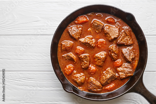 Goulash traditional homemade European beef meat stew soup food with spicy gravy in cast iron pan