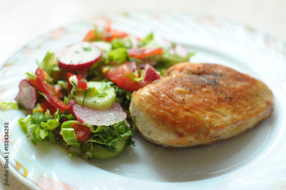 Baked chicken breast with vegetable salad on a white plate Baked chicken breast with vegetable salad on a white plate