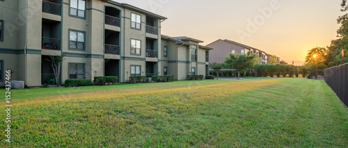 View from grassy backyard of a typical apartment complex building in suburban area at Humble, Texas, US. Sunset with warm light. Panorama style. photo