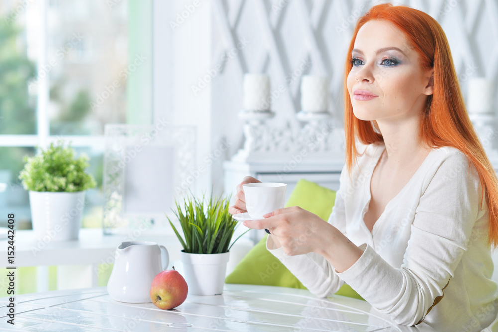 Beautiful woman sitting at a table drinking tea Beautiful woman sitting at a table drinking tea