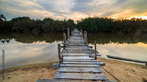 The old wooden bridge over a river at Kg. Pulau Kerengga, Marang Malaysia with sunset scenery photo