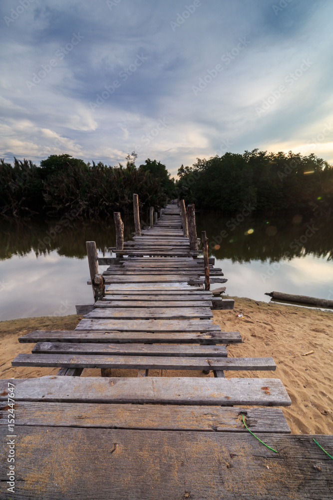 Obraz premium The old wooden bridge over a river at Kg. Pulau Kerengga, Marang Malaysia with sunset scenery