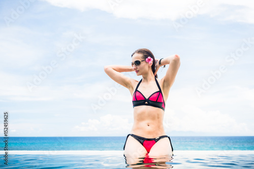 Woman sitting at the edge of infinity pool in hotel resort