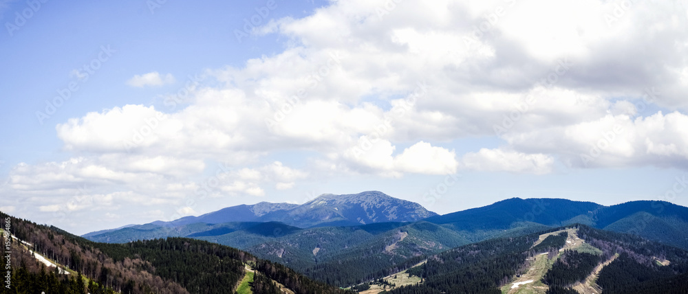 Panoramic shot of the mountains with clouds on the sky