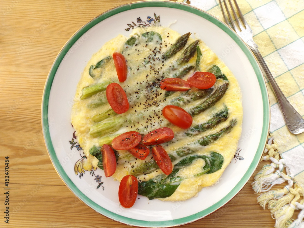 Omelette with asparagus, spinach and cherry tomatoes on a plate