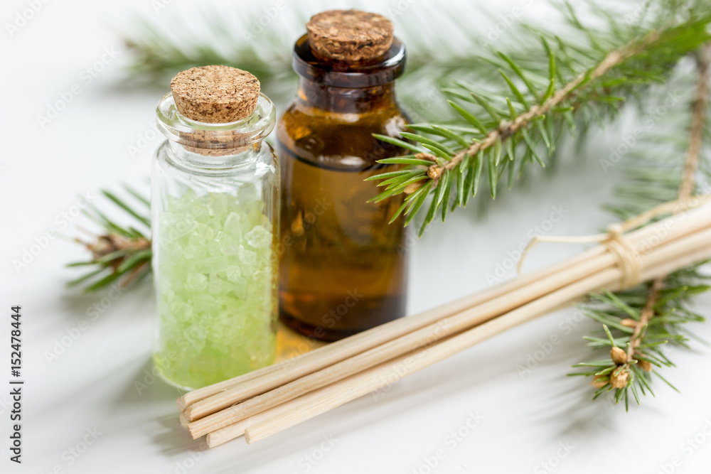 spa with organic spruce oil and sea salt in glass bottles on white table background spa with organic spruce oil and sea salt in glass bottles on white table background