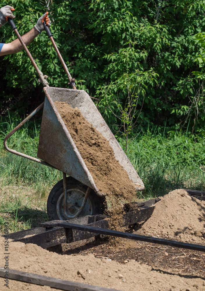The man pours out the clay from the wheelbarrow The man pours out the clay from the wheelbarrow