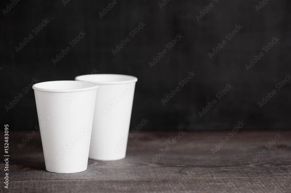Two disposable cups on the dark wooden table Two disposable cups on the dark wooden table