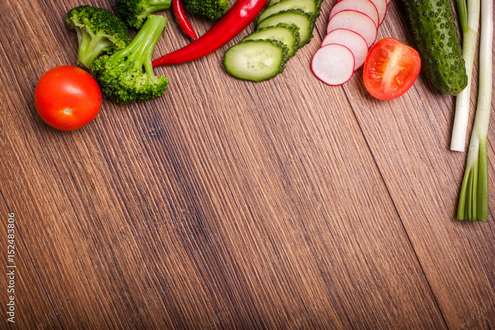 tomato, radish, cucumber, broccoli, onion, chili on a wooden surface. arrangement of sliced vegetables. Top view with copy space for text. Top view with copy space for text tomato, radish, cucumber, broccoli, onion, chili on a wooden surface. arrangement of sliced vegetables. Top view with copy space for text. Top view with copy space for text